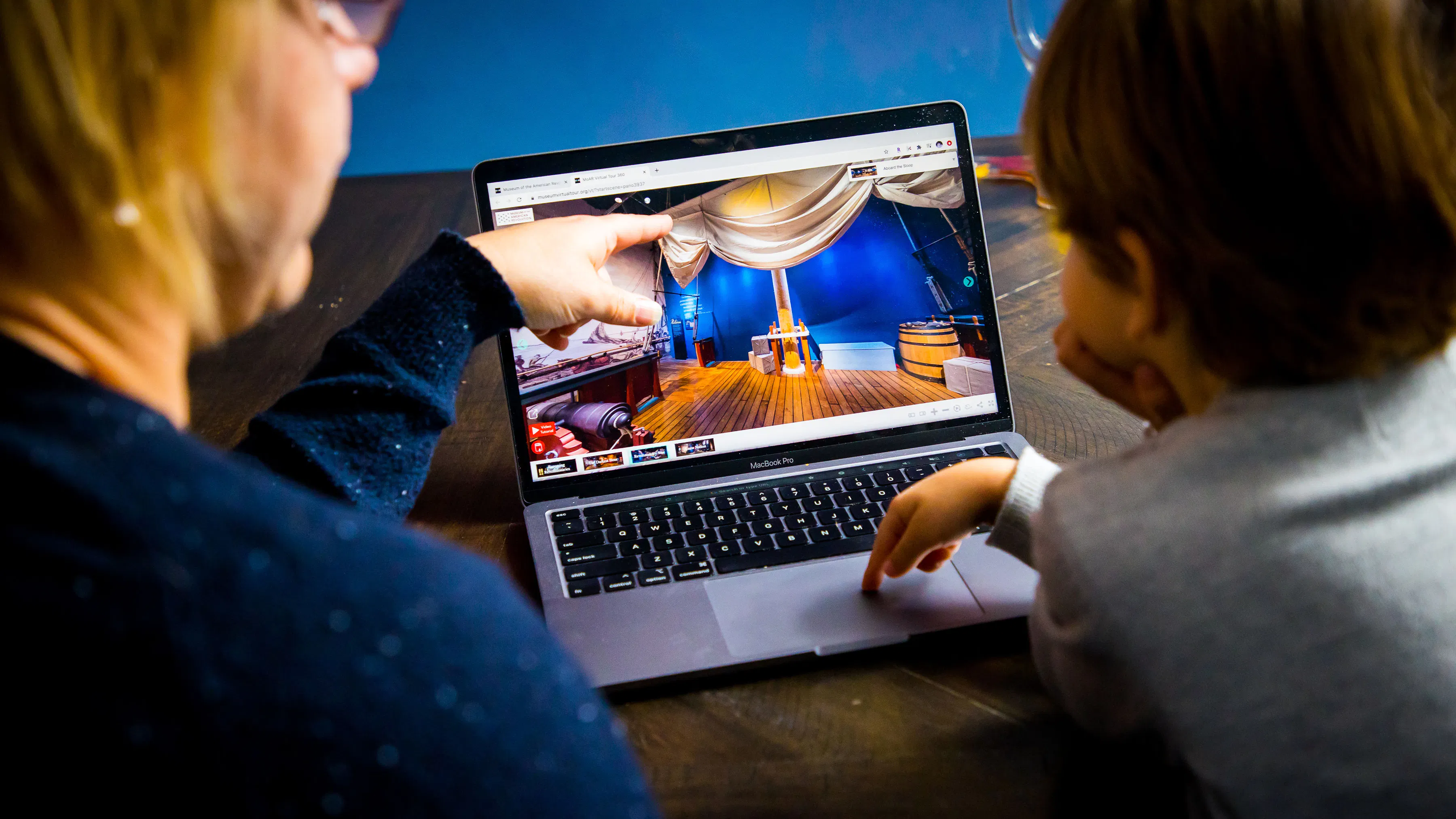 Child and adult browsing the virtual museum tour on their laptop