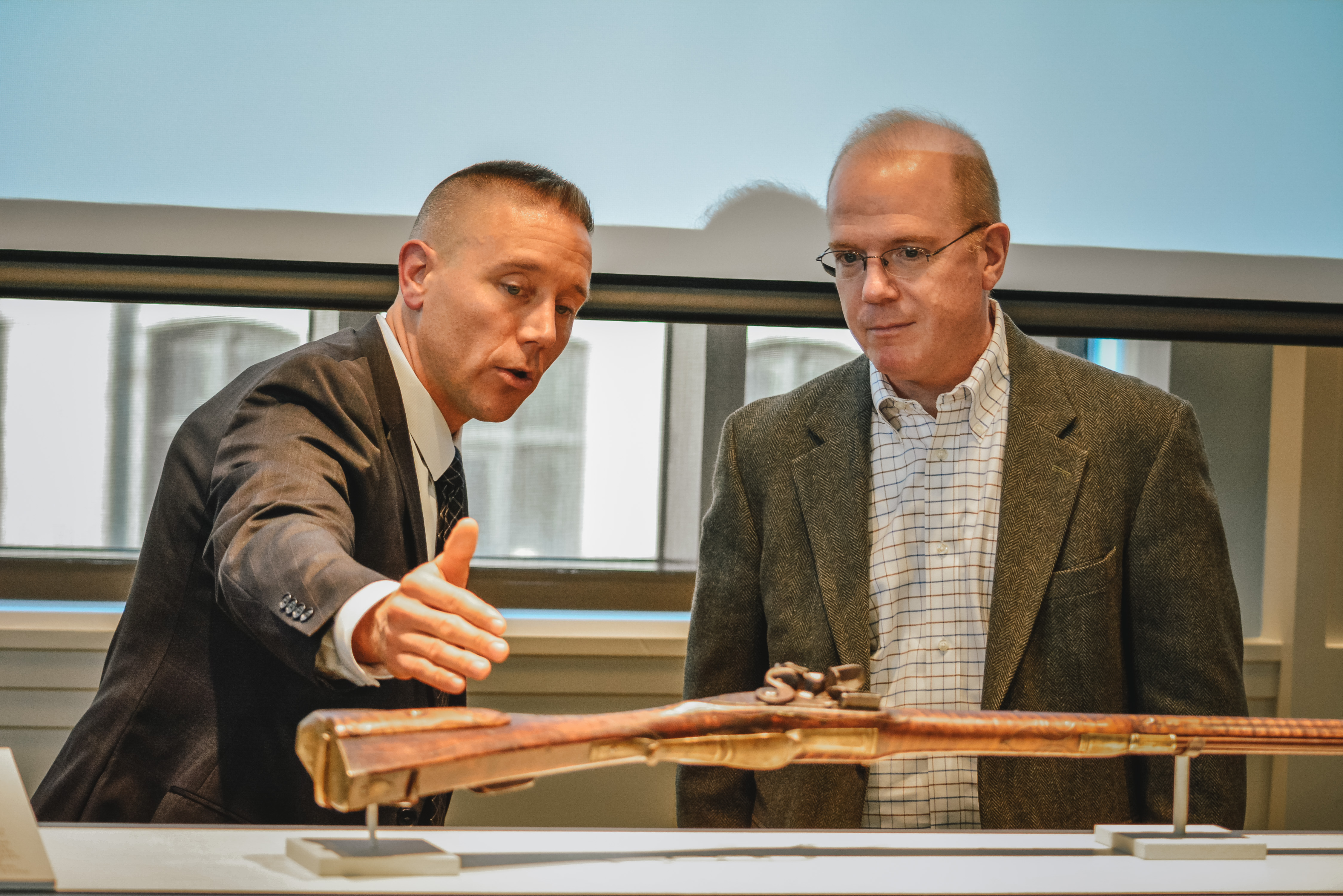 FBI Special Agent Jake Archer points at a detail on a rare firearm made by John Christian Oerter during the Revolutionary era.